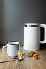 Modern electric kettle, cup of tea and cookies on wooden table in kitchen