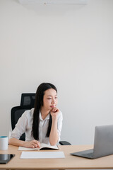 Focused young woman working at a desk with a laptop and documents, embodying remote work and modern office lifestyle.