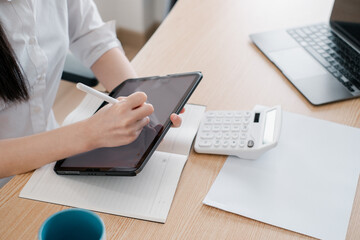 A person using a digital tablet and calculator at a desk, showcasing modern office work and technology integration.