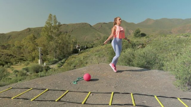 Fit Woman Jumps Rope Doing Sport in Nature with Mountains in the Background. Mujer Fitness Salta a la Comba Haciendo Deporte en la Naturaleza con Monta&ntilde;as de Fondo
