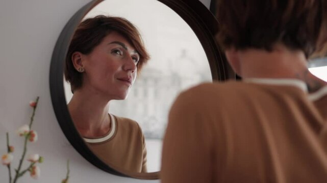Woman admires her reflection in a round mirror, smiling with joy. Radiating confidence and self-love, she embraces positivity during her morning routine