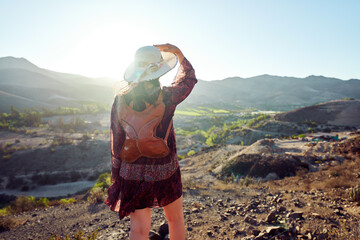 rear view standing Latin woman posing outdoors with the Huasco Valley in the background