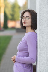 Portrait of a young beautiful dark-haired girl in a dress outdoors.