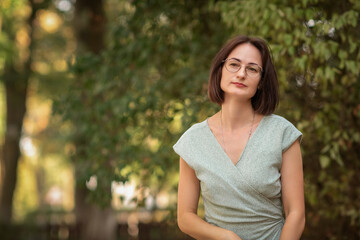 Fototapeta premium Portrait of a young beautiful dark-haired girl in a dress outdoors.