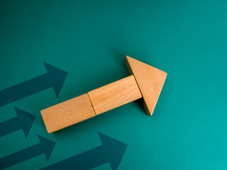 Business growth and technology development, investment grow and leadership concept. Leader, wooden cube block arranged as a big arrow heading up faster than other dark arrows on green background.