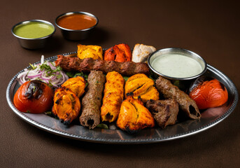 Assorted mix grills with tikka boti seekh kabab of chicken, beef, lamb, mutton bbq platter on table arabian food