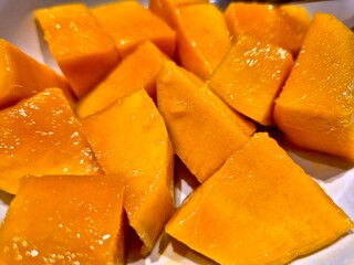 A bowl of sliced mangoes on a wooden table. Photo was taken close up. Selective focus.