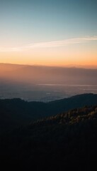 Fototapeta premium a valley with a few trees and mountains in the distance