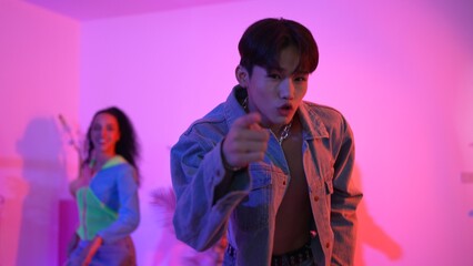 Attractive asian dancer with casual cloth dancing and looking at friend cheering him. Caucasian man and hispanic hipster perform street dancing while turn around and looking at happy team. Regalement.