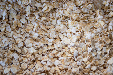 Background with rolled oats in flakes in brown tones. Copy space.