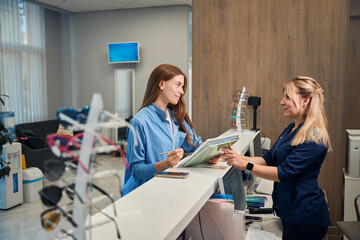 Patient and receptionist discussing paperwork at the counter