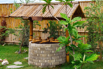 Beautiful artesian well made by bricks and old vintage style wooden dipper made from bamboo and...