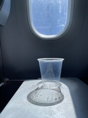 airplane window with empty cup shadow