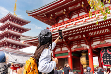 Young female tourist taking a photo of sensoji temple at Asakusa district in Tokyo, Japan