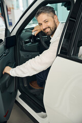 Smiling adult man buying new car, looking at camera