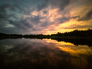 Fototapeta premium Sonnenunterng am See mit dramatischen Himmel 