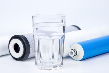 A glass of clean water. Filter cartridges for water isolated. Replacement filter.