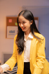 Smiling young asian businesswoman in a yellow jacket and white shirt offers a handshake in a modern office, creating a welcoming and collaborative vibe