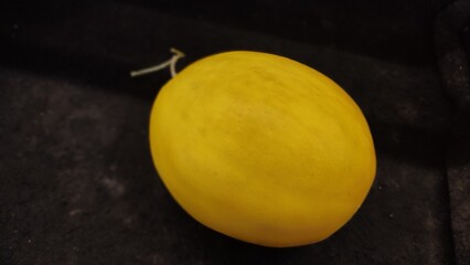 Top view of organic yellow honeydew melon lie on a black table.
