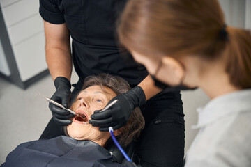 Male doctor treats teeth of elderly lady