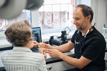 Dental prosthetist is consulting an elderly lady