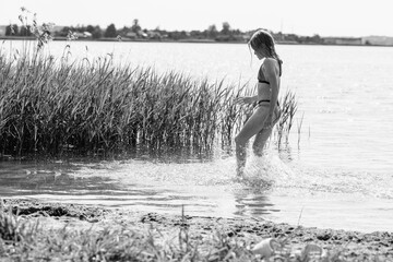 Fototapeta premium Beautiful girl playing on the pond in summer. Black and white photo.