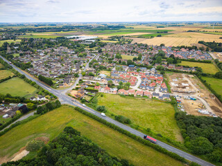 Aerial view of a typical British road bypass seen next to an East Anglia village. New house...
