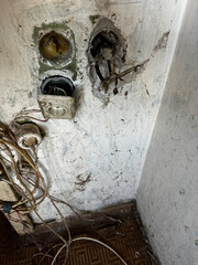Damaged electrical outlets and exposed wiring in an old apartment, highlighting the need for...