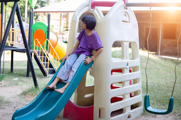 Joyful Children Sliding Down A Playground Slide During A Sunny Afternoon
