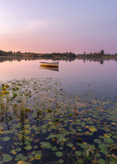 Boat floating on Loch Rusky at sunrise, Scotland, UK