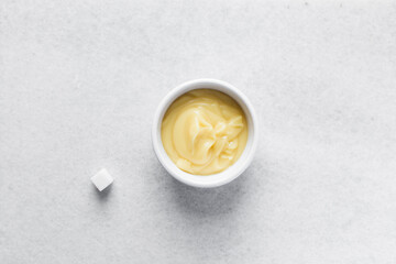Overhead view of nigerian akamu in a white bowl with sugar and milk, pap akamu or ogi in a white bowl