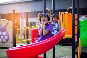 Joyful Children Sliding Down A Playground Slide During A Sunny Afternoon