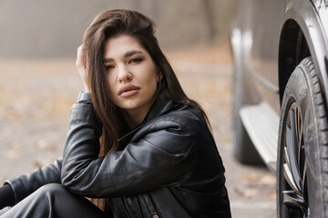 Urban Elegance: A Portrait of a Woman in a Leather Jacket Beside a Car