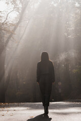 A Solitary Figure Walking in a Misty Forest at Dawn