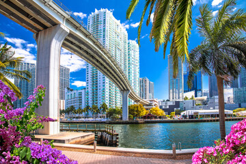 Miami downtown skyline and futuristic mover train above Miami river flower view