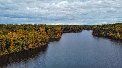 Fototapeta premium Drone View of Lake Surrounded by Fall Foliage