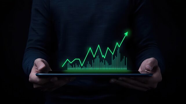 A person holds a tablet displaying a glowing green graph, illustrating upward trends and positive growth against a dark background.