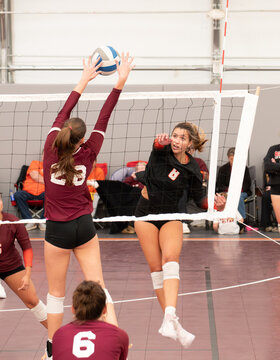 Female college volleyball player getting blocked by a single right side blocker