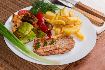 Grilled boneless pork chop with baked vegetables and french fries