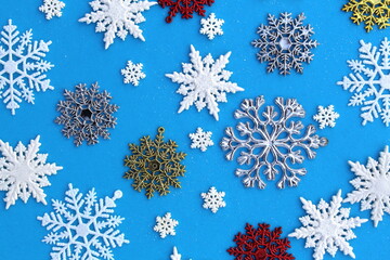 Christmas texture of multicolored snowflakes lying on a blue background.