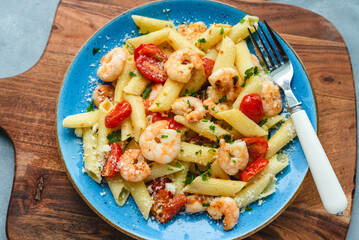 Penne pasta with shrimps and cherry tomatoes in butter and garlic sauce