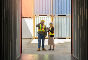 Two loading or warehouse workers standing in front of empty cargo container for inspection. Pregnage woman holding digital tablet and man using walkie talkie in shipping yard