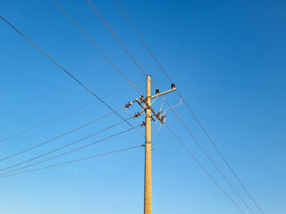 Network of electric cables on electric poles with a clear blue sky in the afternoon