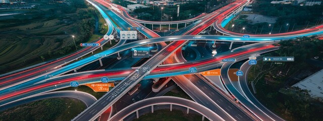 A complex highway interchange at night with cars creating streaks of light.