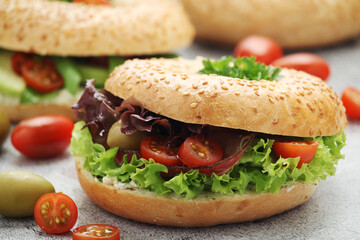 Sesame bagels with tomatoes, ham and olives