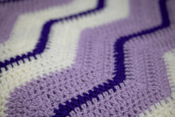  close-up of grandma's retro zigzag striped blanket, in white, royal purple and lilac or lavender purple, crocheted or knitted, grandma's house, cozy and warm, diagonal