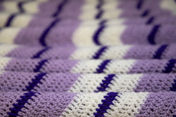 close-up of grandma's retro zigzag striped blanket, in white, lilac or lavender and royal purple, crocheted or knitted, grandma's house, cozy and warm, rippling