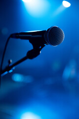 Obraz premium A wired microphone with a stand on a blue stage background.