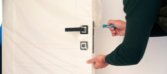 Man fixing the door handle with screwdriver