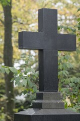Dark stone cross standing in cemetery representing faith and remembrance